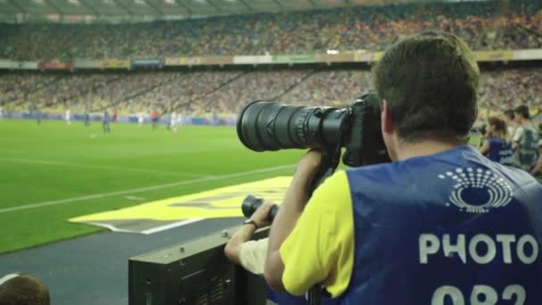 Een fotograaf, fotografen met een camera in een stadion tijdens een voetbalwedstrijd. — Stockvideo