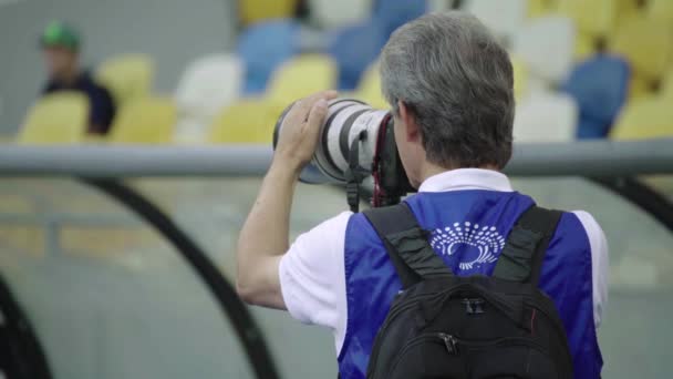 Een fotograaf, fotografen met een camera in een stadion tijdens een voetbalwedstrijd. — Stockvideo