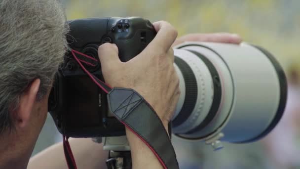 Un fotógrafo, fotógrafos con una cámara en un estadio durante un partido de fútbol . — Vídeos de Stock