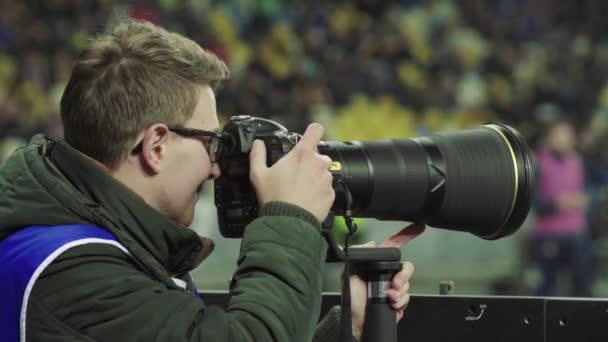 Een fotograaf, fotografen met een camera in een stadion tijdens een voetbalwedstrijd. — Stockvideo