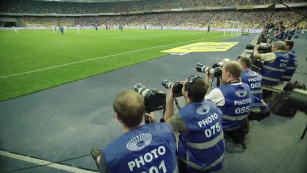 Un photographe, des photographes avec un appareil photo dans un stade pendant un match de football . — Video