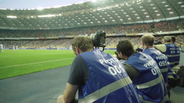 Un fotógrafo, fotógrafos con una cámara en un estadio durante un partido de fútbol . — Vídeos de Stock