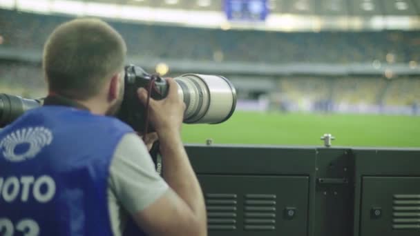 En fotograf, fotografer med kamera på et stadion under en fotballkamp. . – stockvideo