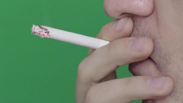 Un cigarrillo en la boca de un fumador. Primer plano. En cámara lenta. Chroma Key. Fondo verde . — Vídeos de Stock