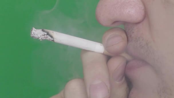 Cigaretta egy dohányos szájában. Közelkép. Lassú mozgás. Krómkulcs. Zöld háttér. — Stock videók