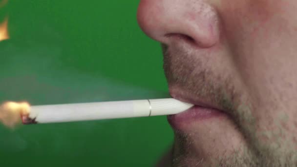 Un cigarrillo en la boca de un fumador. Primer plano. Chroma Key. Fondo verde . — Vídeos de Stock