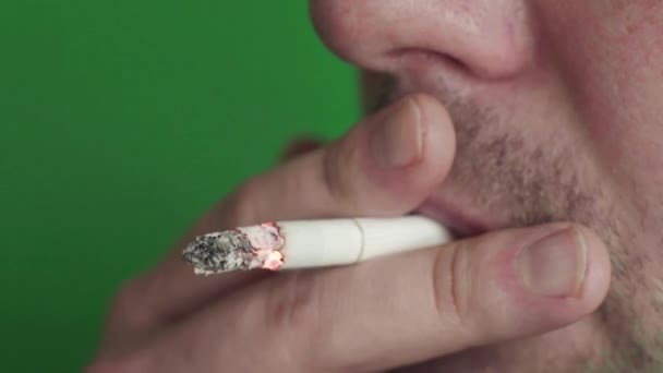 Cigaretta egy dohányos szájában. Közelkép. Krómkulcs. Zöld háttér. — Stock videók