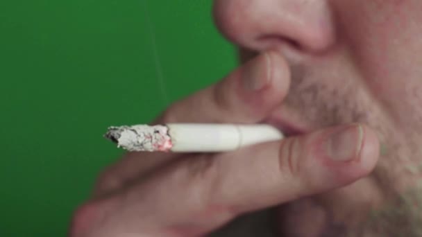 Cigaretta egy dohányos szájában. Közelkép. Krómkulcs. Zöld háttér. — Stock videók