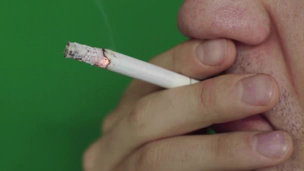 Un cigarrillo en la boca de un fumador. Primer plano. Chroma Key. Fondo verde . — Vídeo de stock
