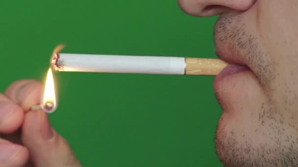 Un cigarrillo en la boca de un fumador. Primer plano. En cámara lenta. Chroma Key. Fondo verde . — Vídeo de stock