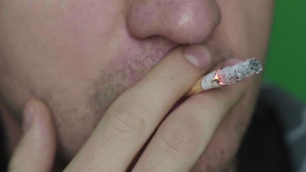 Cigaretta egy dohányos szájában. Közelkép. Lassú mozgás. Krómkulcs. Zöld háttér. — Stock videók