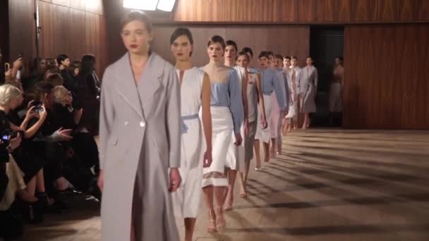 ファッションショーモデルのグループは、キャットウォーク上を歩く。スローモーション — ストック動画