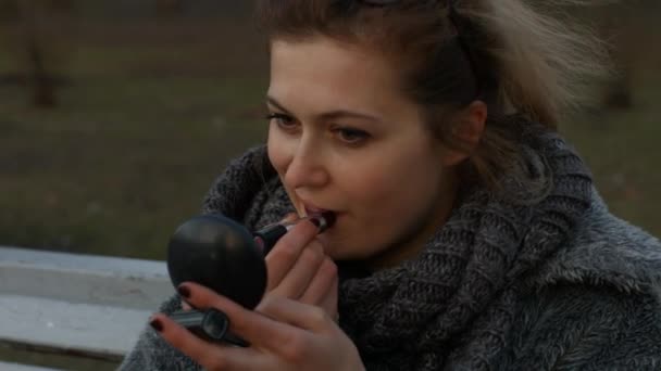 女の子は公園に座って唇をペイントします。キエフ。ウクライナ — ストック動画