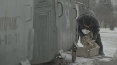 Dilenci evsiz bir serseri çöp tenekesinde yiyecek arıyor. Kyiv. Ukrayna