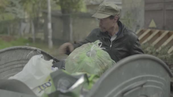乞食のホームレスの男の罠は、ゴミ箱で食料を探していることができます。キエフ。ウクライナ — ストック動画