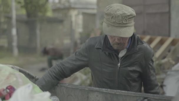 A beggar homeless man tramp is looking for food in a trash can. Kyiv. Ukraine — Stock Video