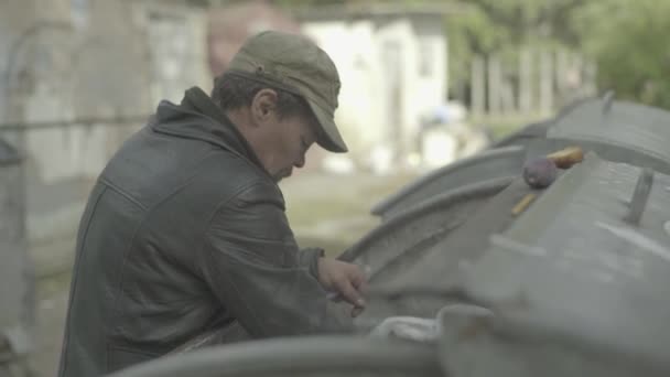 A beggar homeless man tramp is looking for food in a trash can. Kyiv. Ukraine — Stock Video