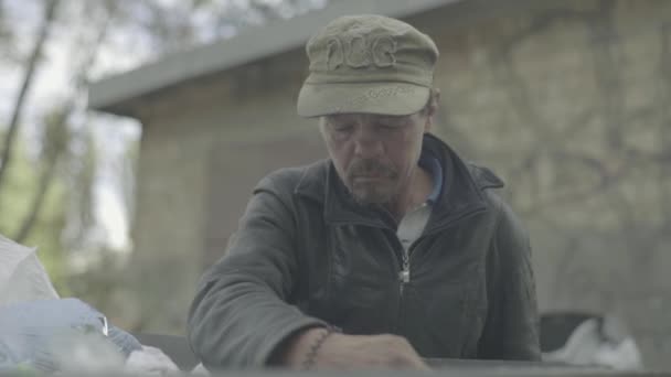 A beggar homeless man tramp is looking for food in a trash can. Kyiv. Ukraine — Stock Video