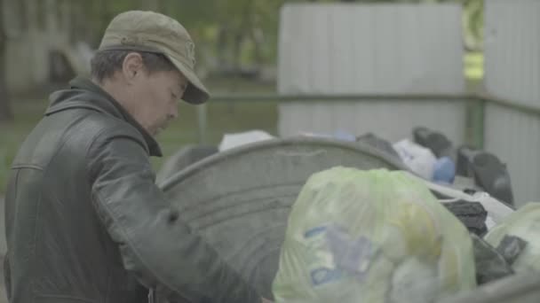 Žebrák bezdomovec tulák hledá jídlo v popelnici. Kyjev. Ukrajina — Stock video
