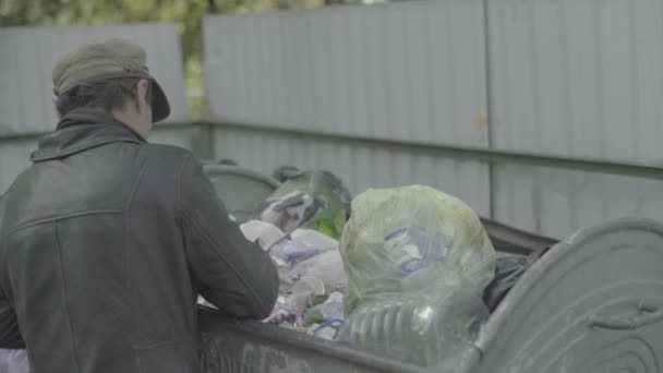 Un vagabundo mendigo sin hogar está buscando comida en un cubo de basura. Kiev. Ucrania — Vídeos de Stock