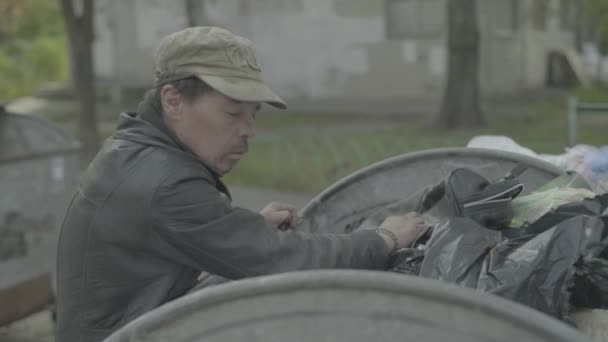 Dilenci evsiz bir serseri çöp tenekesinde yiyecek arıyor. Kyiv. Ukrayna — Stok video