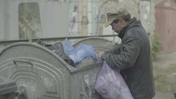 Un barbone barbone mendicante sta cercando del cibo in un bidone della spazzatura. Kiev. Ucraina — Video Stock