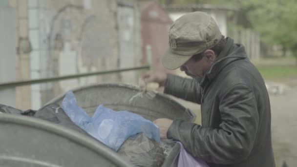 Un barbone barbone mendicante sta cercando del cibo in un bidone della spazzatura. Kiev. Ucraina — Video Stock