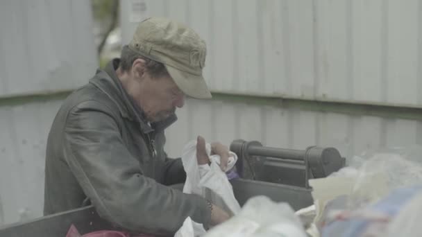 Un vagabundo mendigo sin hogar está buscando comida en un cubo de basura. Kiev. Ucrania — Vídeos de Stock