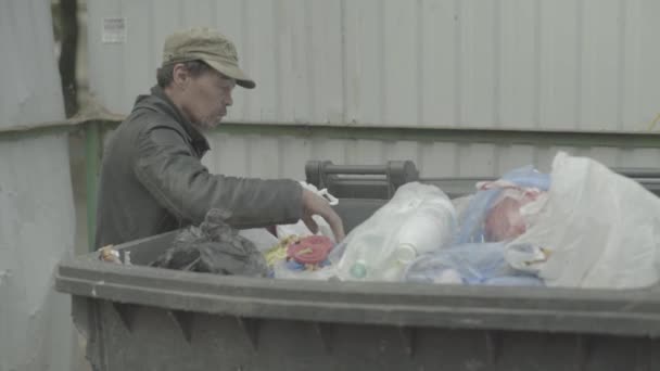 A beggar homeless man tramp is looking for food in a trash can. Kyiv. Ukraine — Stock Video