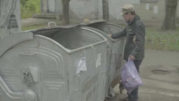 A beggar homeless man tramp is looking for food in a trash can. Kyiv. Ukraine — Stock Video