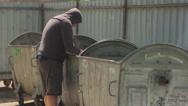 Un vagabundo mendigo sin hogar está buscando comida en un cubo de basura. Kiev. Ucrania — Vídeos de Stock