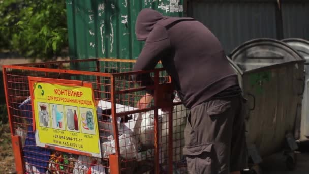 Un vagabundo mendigo sin hogar está buscando comida en un cubo de basura. Kiev. Ucrania — Vídeos de Stock