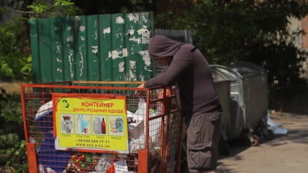 Бездомный бродяга ищет еду в мусорном баке. Киев. Украина — стоковое видео