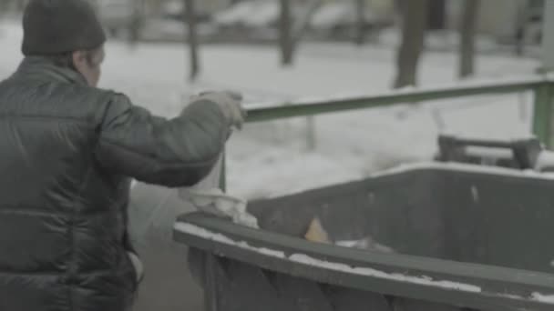 Egy koldus hajléktalan csavargó ételt keres egy kukában. Kijevben. Ukrajna — Stock videók