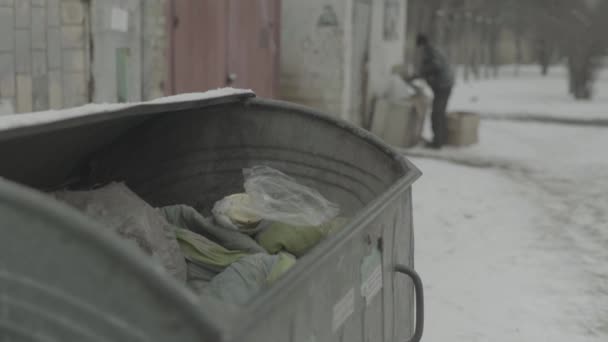 Un vagabundo mendigo sin hogar está buscando comida en un cubo de basura. Kiev. Ucrania — Vídeos de Stock