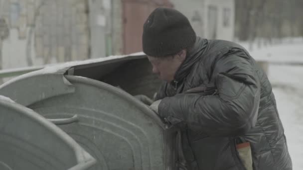 Bezdomny żebrak szuka jedzenia w koszu na śmieci. Kijów. Ukraina — Wideo stockowe