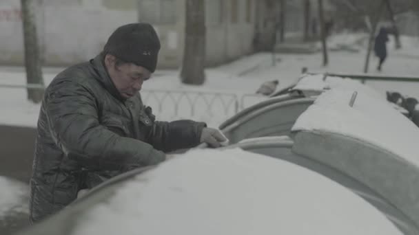 Um mendigo vagabundo anda à procura de comida num caixote do lixo. Kiev. Ucrânia — Vídeo de Stock