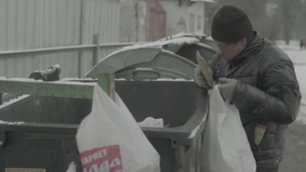 Ein Bettler, der obdachlos ist, sucht in einem Mülleimer nach Essen. Kiew. Ukraine — Stockvideo