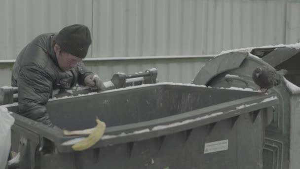 Um mendigo vagabundo anda à procura de comida num caixote do lixo. Kiev. Ucrânia — Vídeo de Stock
