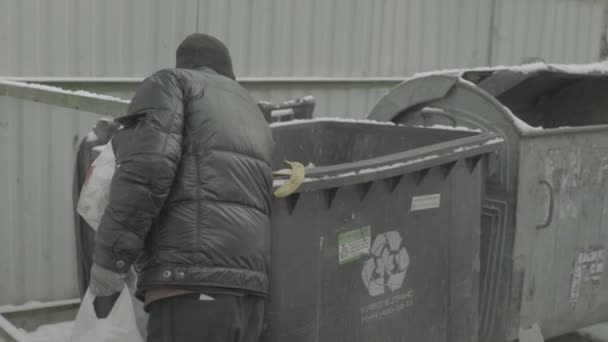 Un vagabundo mendigo sin hogar está buscando comida en un cubo de basura. Kiev. Ucrania — Vídeo de stock