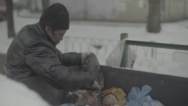 Ein Bettler, der obdachlos ist, sucht in einem Mülleimer nach Essen. Kiew. Ukraine — Stockvideo