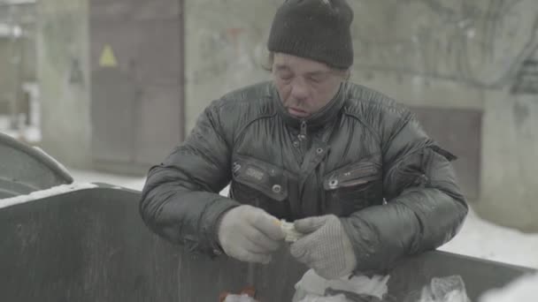 A beggar homeless man tramp is looking for food in a trash can. Kyiv. Ukraine — Stock Video
