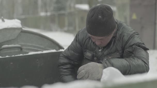 Um mendigo vagabundo anda à procura de comida num caixote do lixo. Kiev. Ucrânia — Vídeo de Stock
