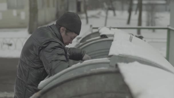 Bezdomny żebrak szuka jedzenia w koszu na śmieci. Kijów. Ukraina — Wideo stockowe