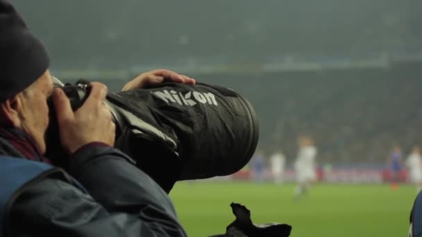 A photographer photographers with a camera in a stadium during a football match. — Stock Video