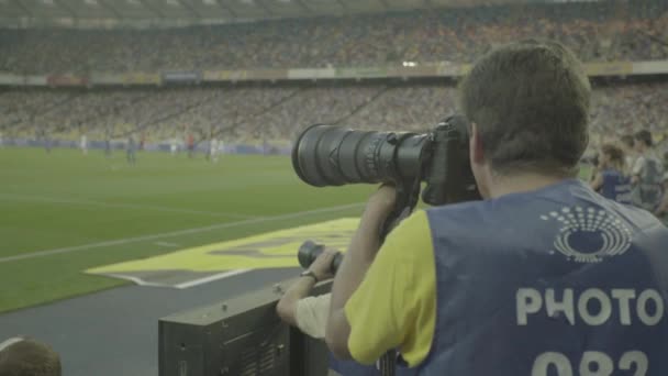 Ein Fotograf mit einer Kamera in einem Stadion während eines Fußballspiels. — Stockvideo