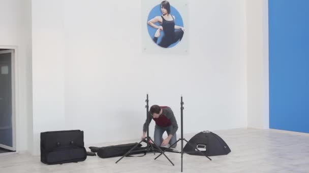 Homem fotógrafo prepara o equipamento antes da sessão de fotos no estúdio — Vídeo de Stock