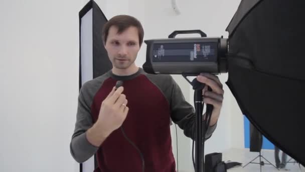 Man photographer prepares the equipment before the photo session in the studio — Stock Video