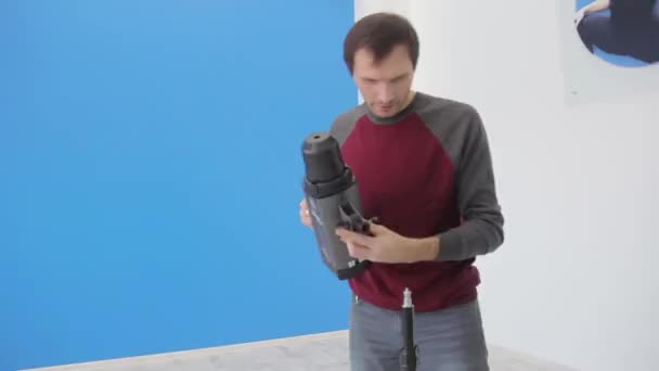 Man photographer prepares the equipment before the photo session in the studio — 비디오