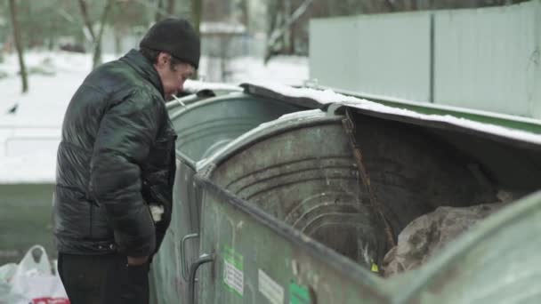 A beggar homeless man tramp is looking for food in a trash can. Kyiv. Ukraine — Stock Video